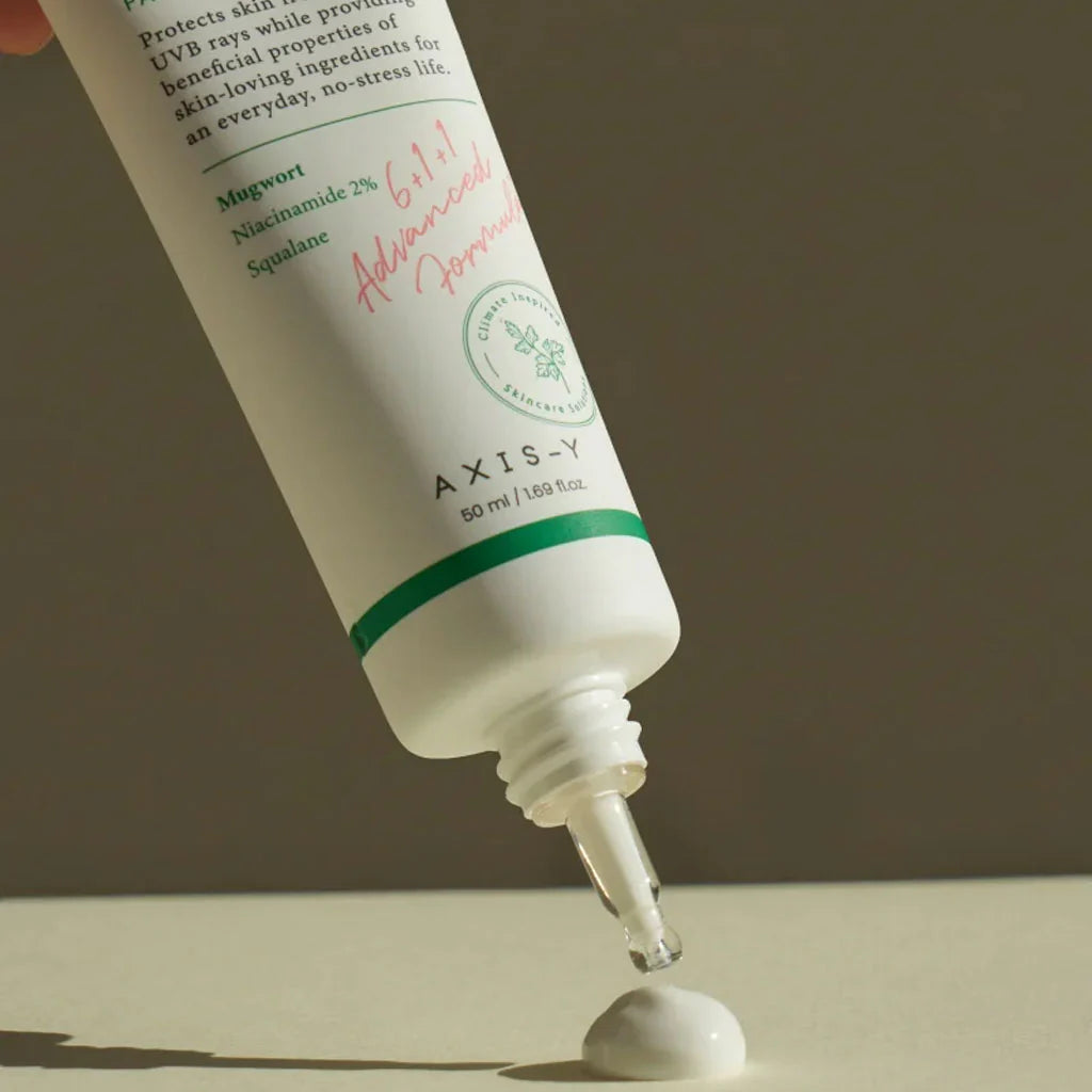 Close-up of Axis-Y sunscreen tube with cream being dispensed from nozzle.