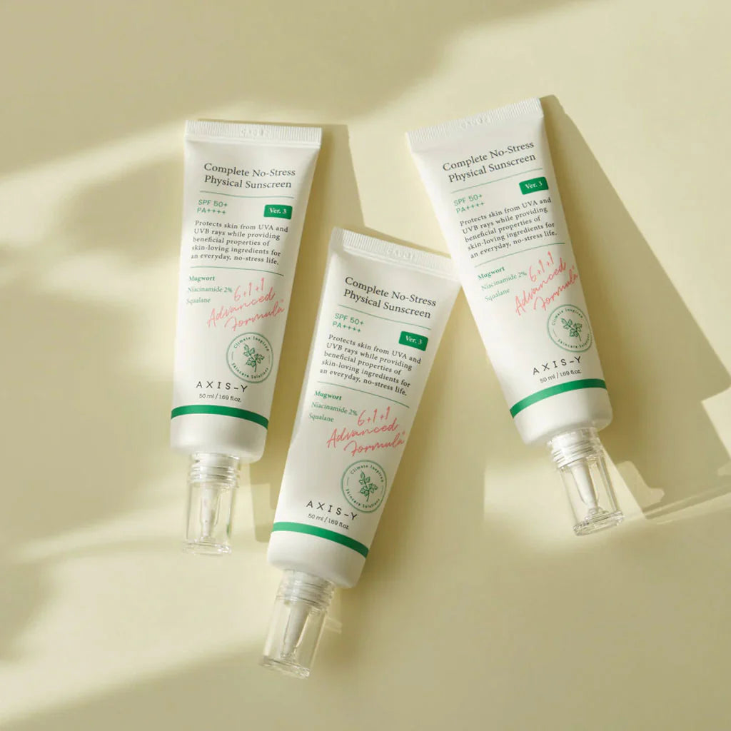Axis-Y Complete No-Stress Sunscreen SPF 50+ tubes in a light cream background flat lay.