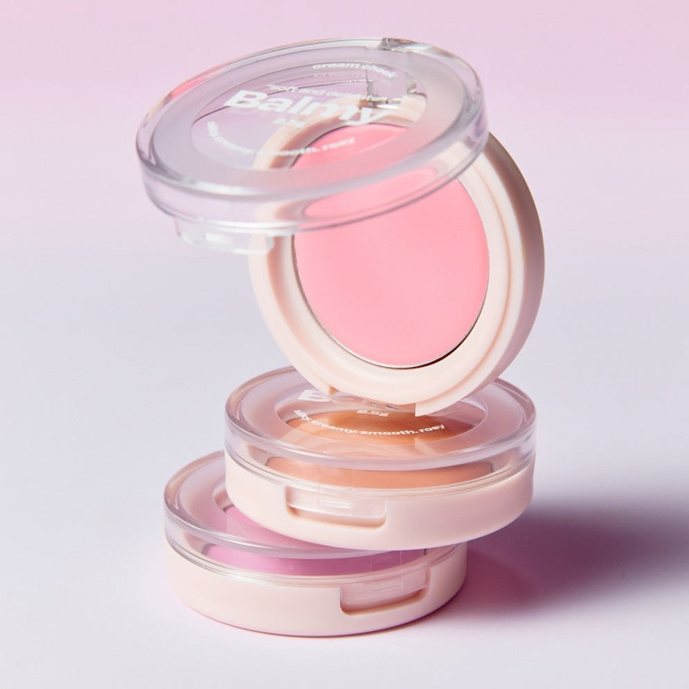 Opened and stacked Balmy Cream Cheek compacts showing a variety of soft, rosy cheek colors.