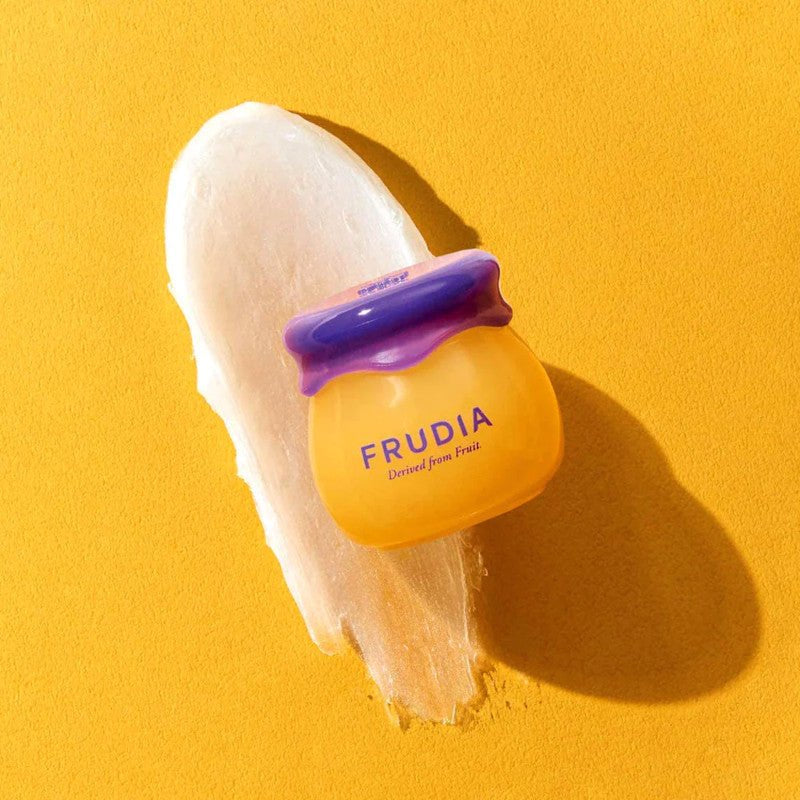 Frudia Blueberry Honey Lip Balm on balm smear with yellow background.