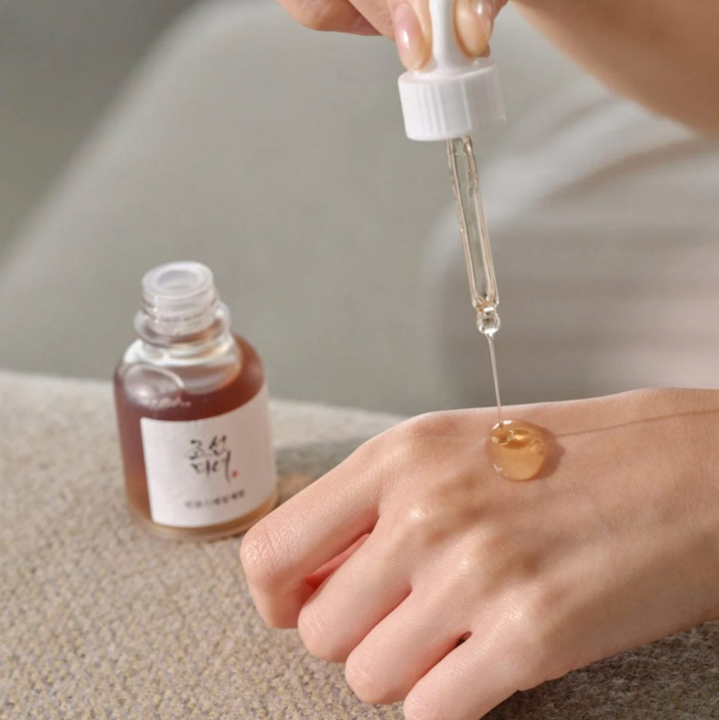 Applying Beauty of Joseon Revive Serum drop onto hand with glass dropper.