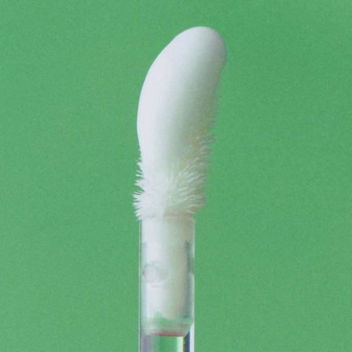 Close-up of Alternative Stereo Steaming Milk lip applicator – soft white doe-foot on green background.