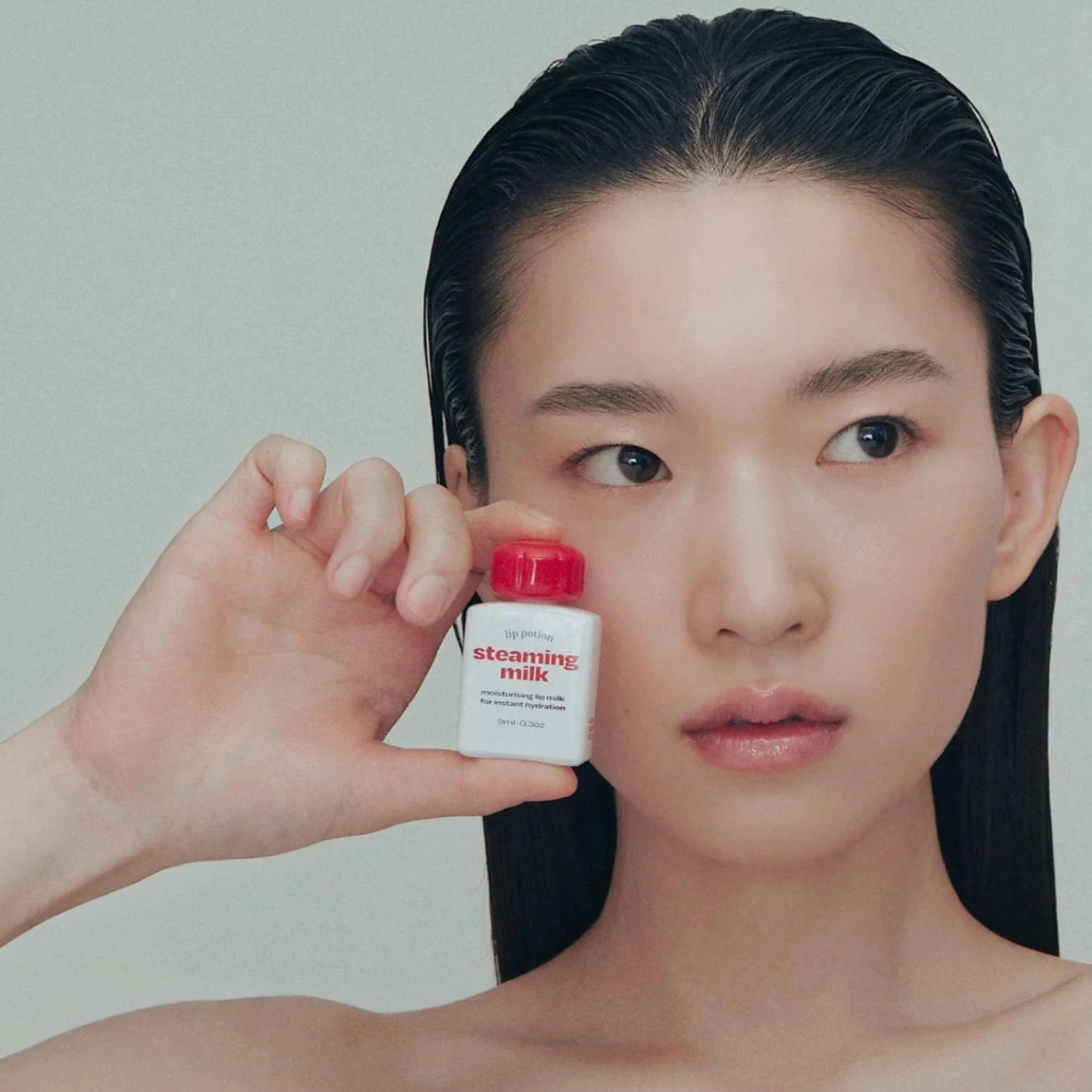Model holding Alternative Stereo Steaming Milk – moisturizing lip potion for soft, hydrated lips.