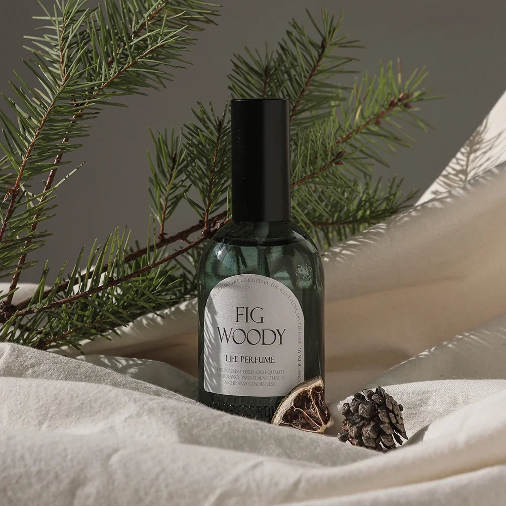 W.Dressroom Fig Woody Life Perfume bottle styled with pine branches and winter props.