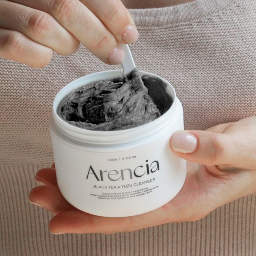 Arencia Black Tea & Yuzu Cleanser being scooped by hand using a spatula.