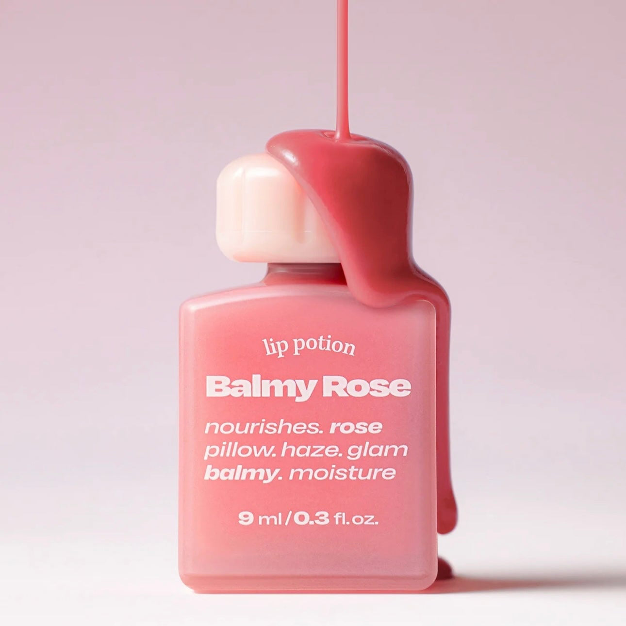 Alternative Stereo Balmy Rose with pink tint dripping over cap – creamy rose lip potion bottle.