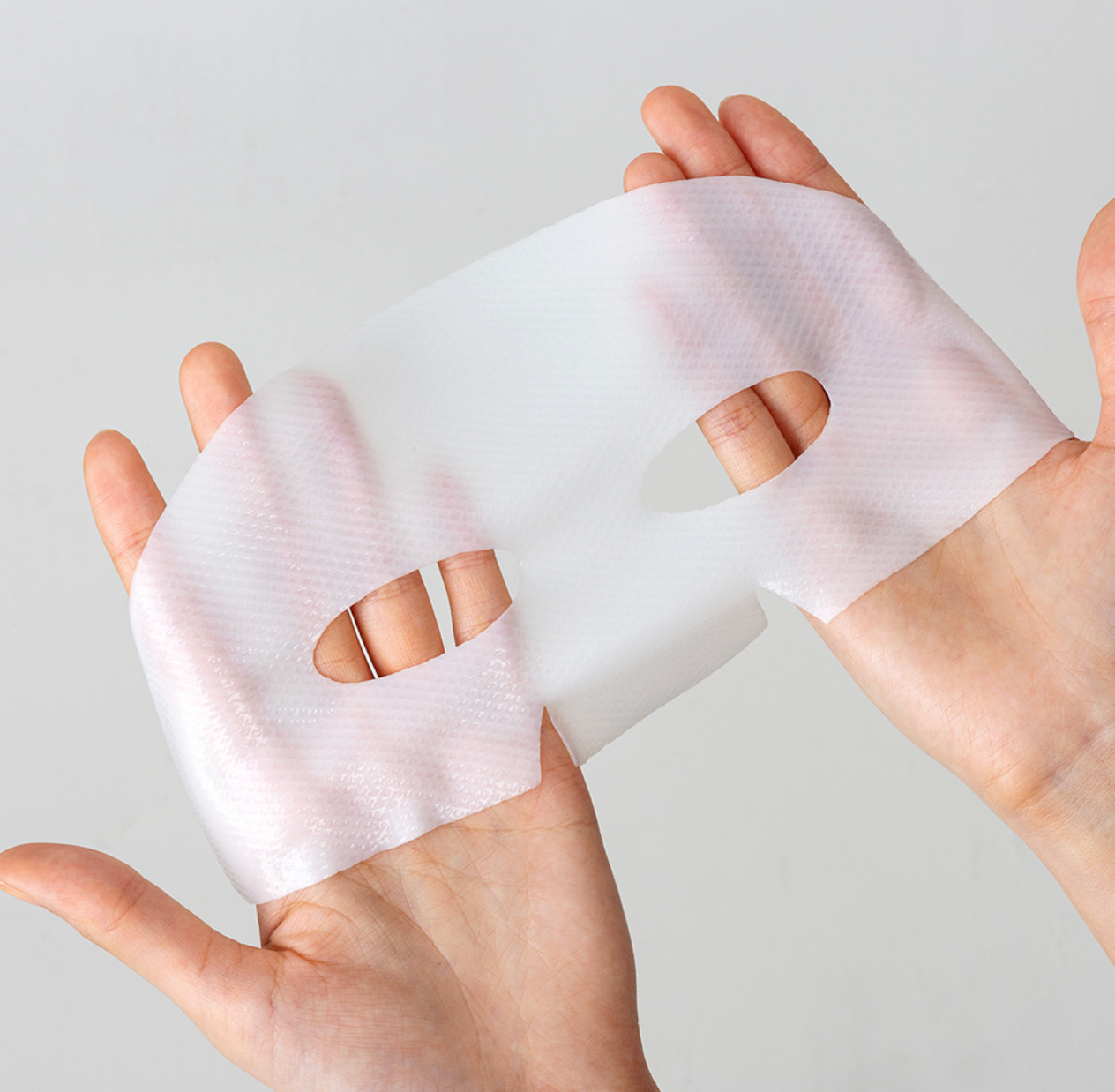 Dermafix Real Collagen Mask sheet shown stretched on hands to highlight texture and coverage.