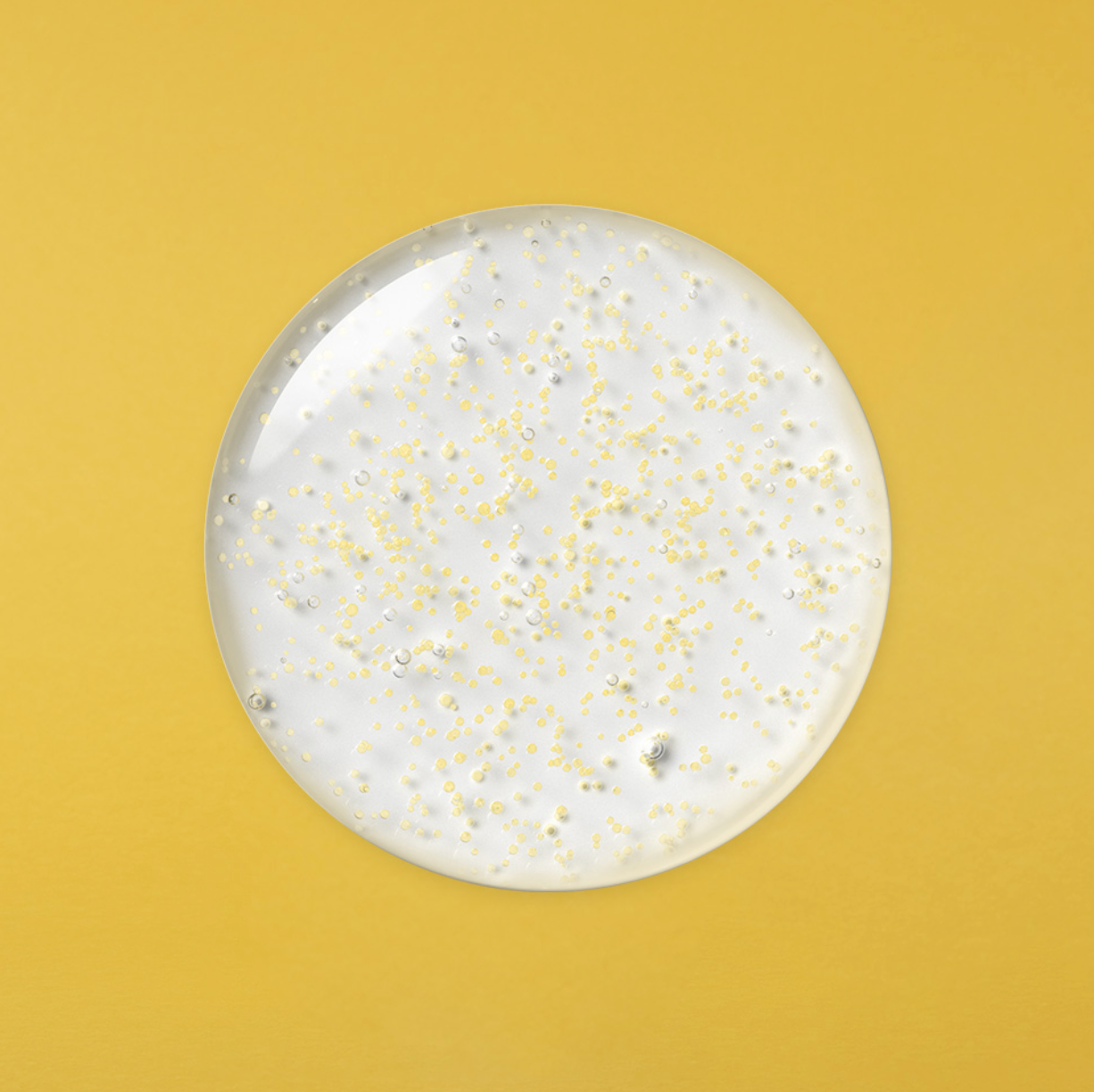 Close-up of Vita Collagen ampoule texture with visible yellow capsules on yellow background.