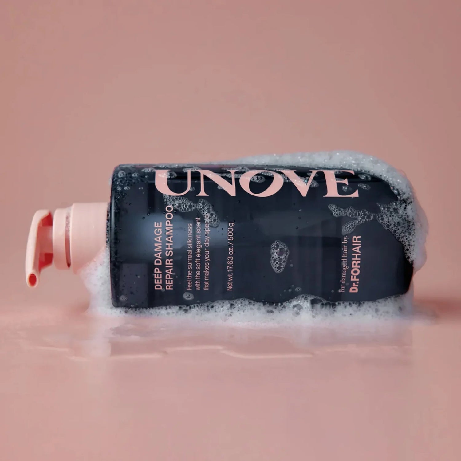 UNOVE Deep Damage Repair Shampoo bottle lying sideways in bubbly foam.